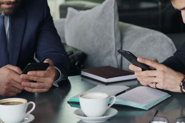 Primo piano di mani di manager che consultano il telefono durante una riunione aziendale