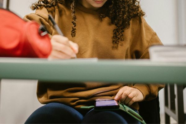 Aula di concorso pubblico dove alcuni candidati consultano di nascosto i propri smartphone