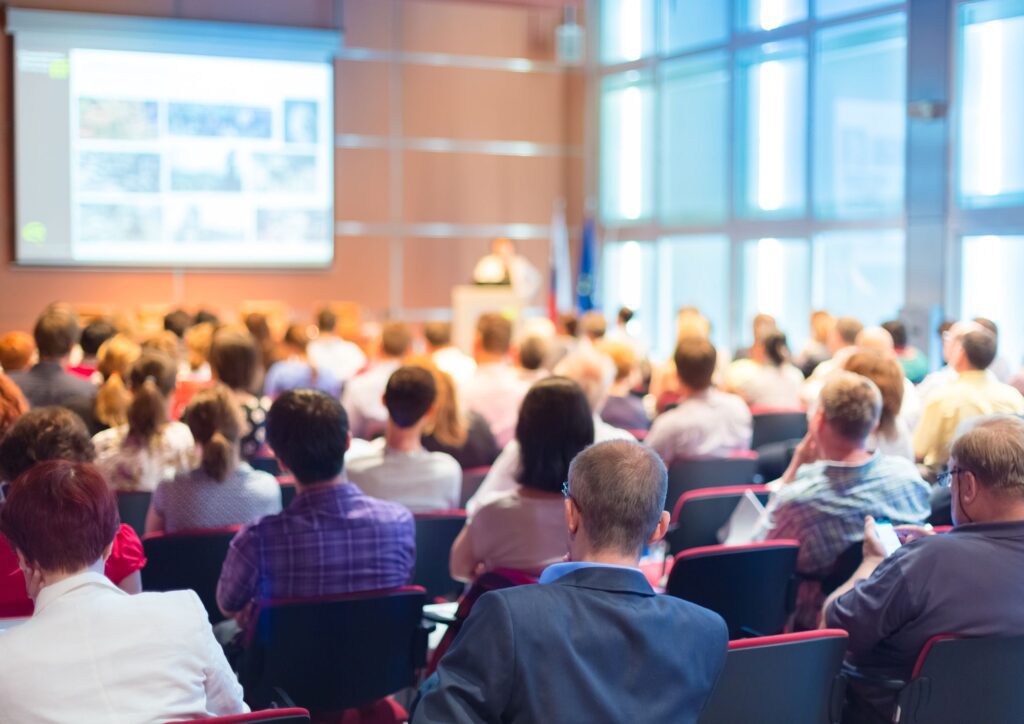 Sala conferenze con pubblico attento a una presentazione